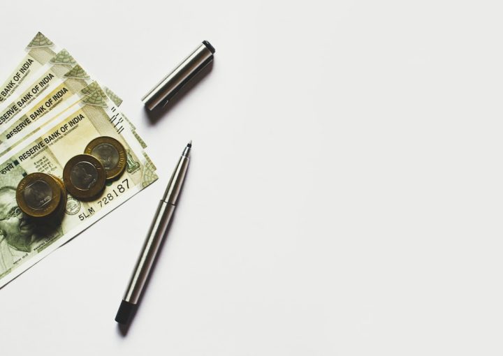 gray pen beside coins on Indian rupee banknotes